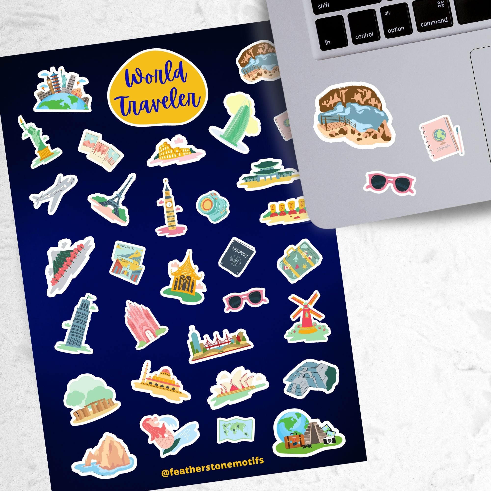 Our World Traveler sticker sheet has sticker images of iconic travel destinations! This sheet has a black background with over 30 different stickers including the Statue of Liberty, Easter Island, Stonehenge, and a passport and camera. This image shows the sticker sheet next to an open laptop with stickers of the Grand Canyon, sunglasses, and a travel notebook and pen, applied below the keyboard.