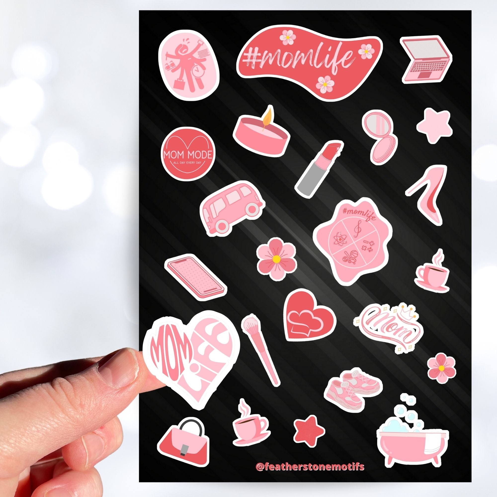Let's celebrate mom! Mom's can do it all, and this pink aesthetic sticker sheet has sticker images of things that moms, and non-moms, enjoy like - candles, bubble baths, makeup, or coffee. This image shows a hand holding a sticker that says "Mom Life" in the shape of a heart above the sticker sheet.